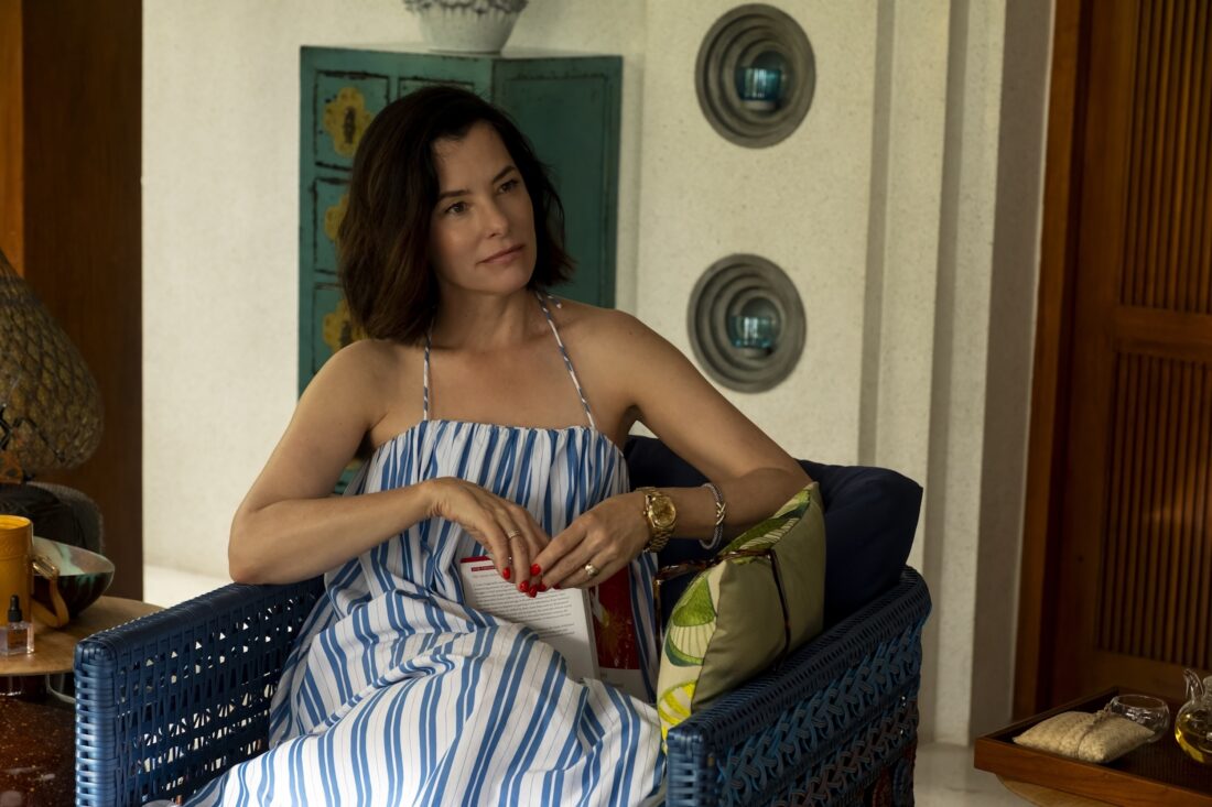 A woman in a sundress sits in a chair